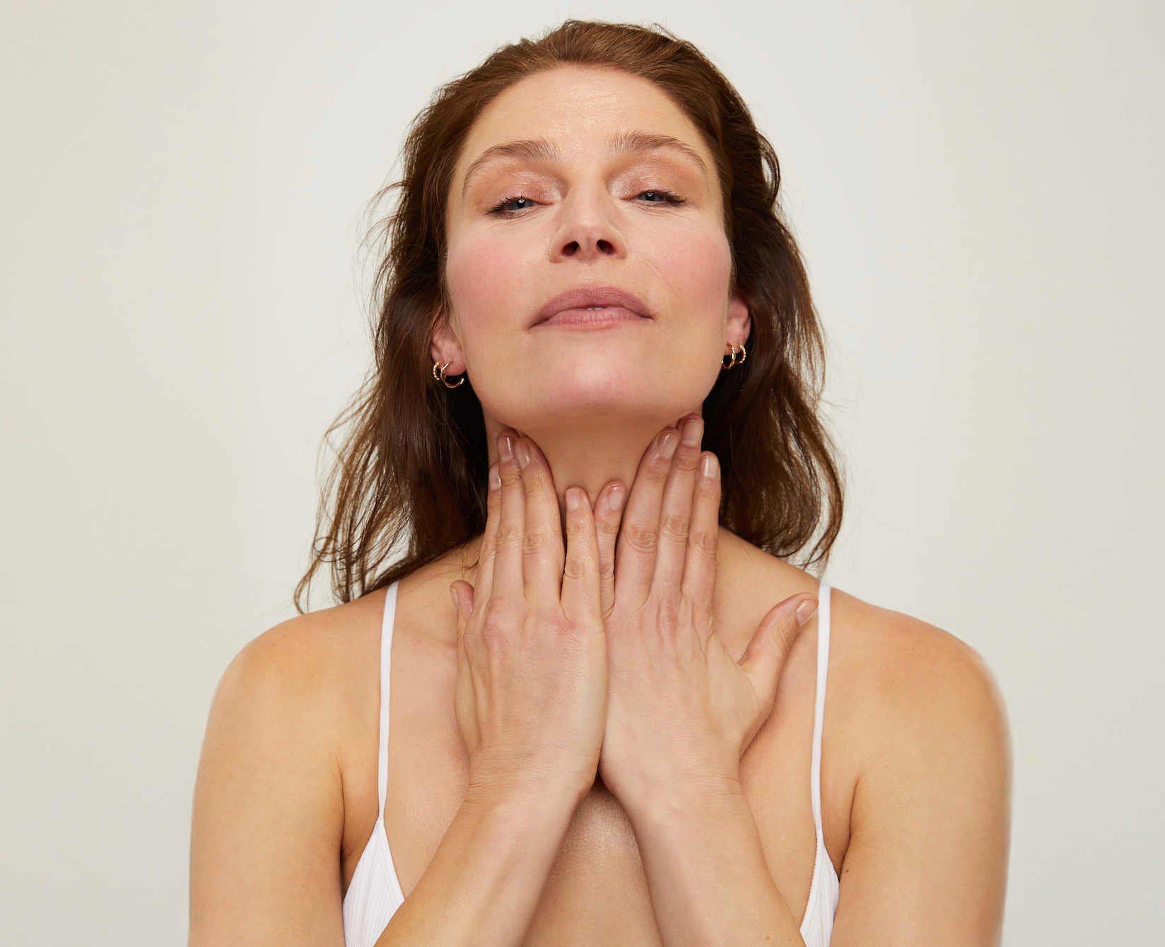 Woman with hands on neck, applying Body Oil
