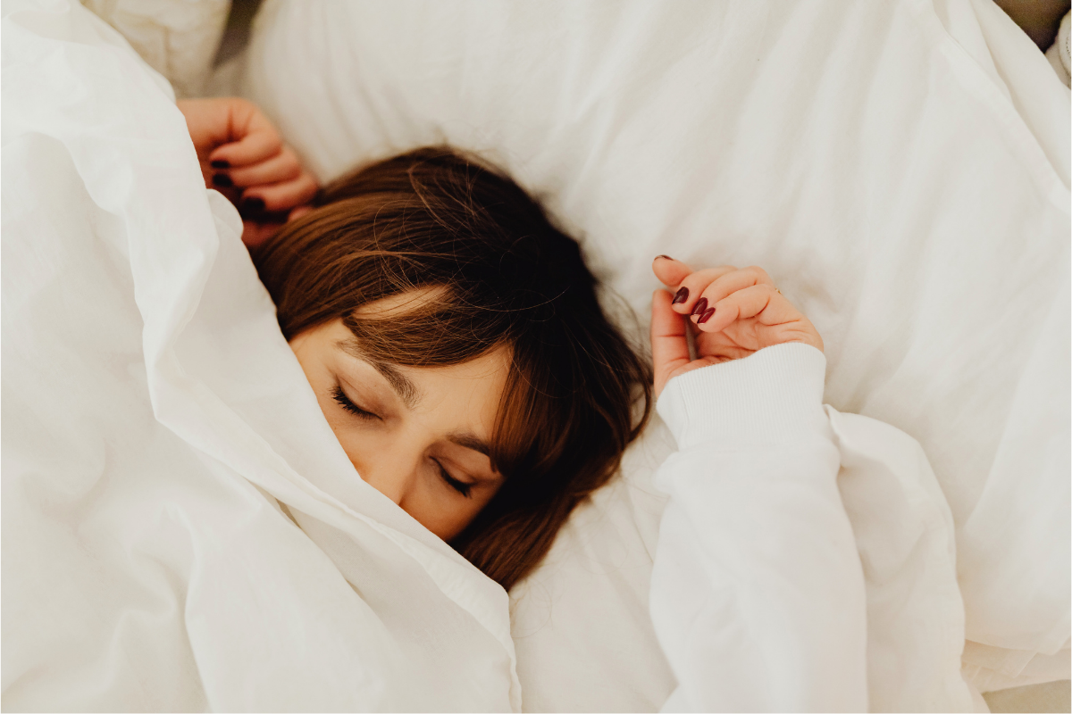 Woman sleeping under sheet in bed