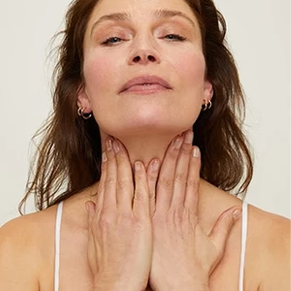 Woman with her neck and collar bone against a plain background