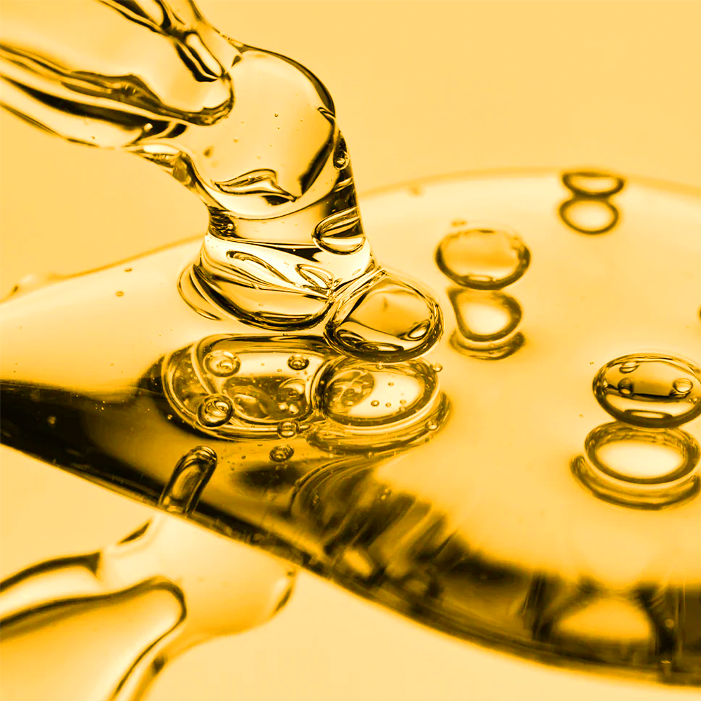 Close-up of a dropper with clear liquid on a yellow background