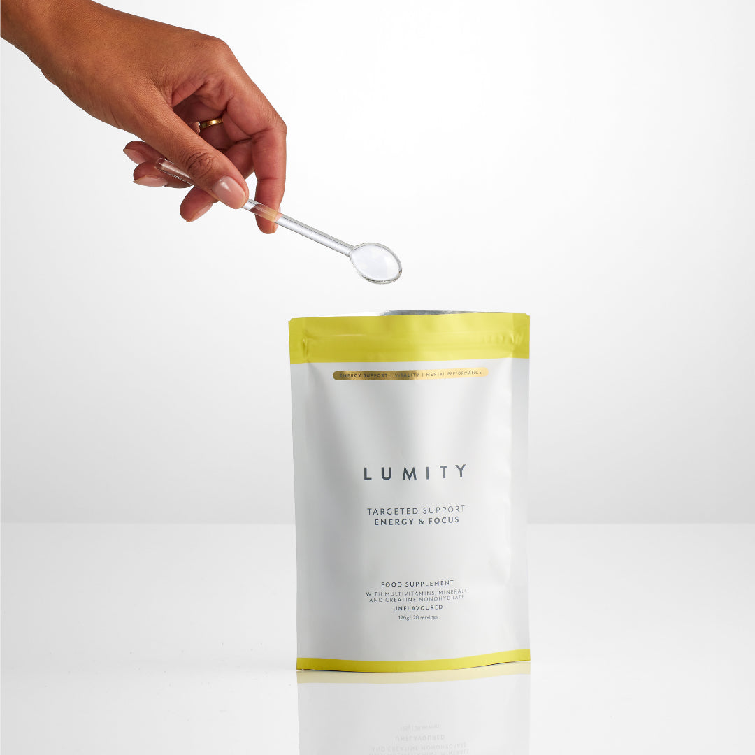 Lumity supplement pouch with a hand using a spoon to scoop out powder.