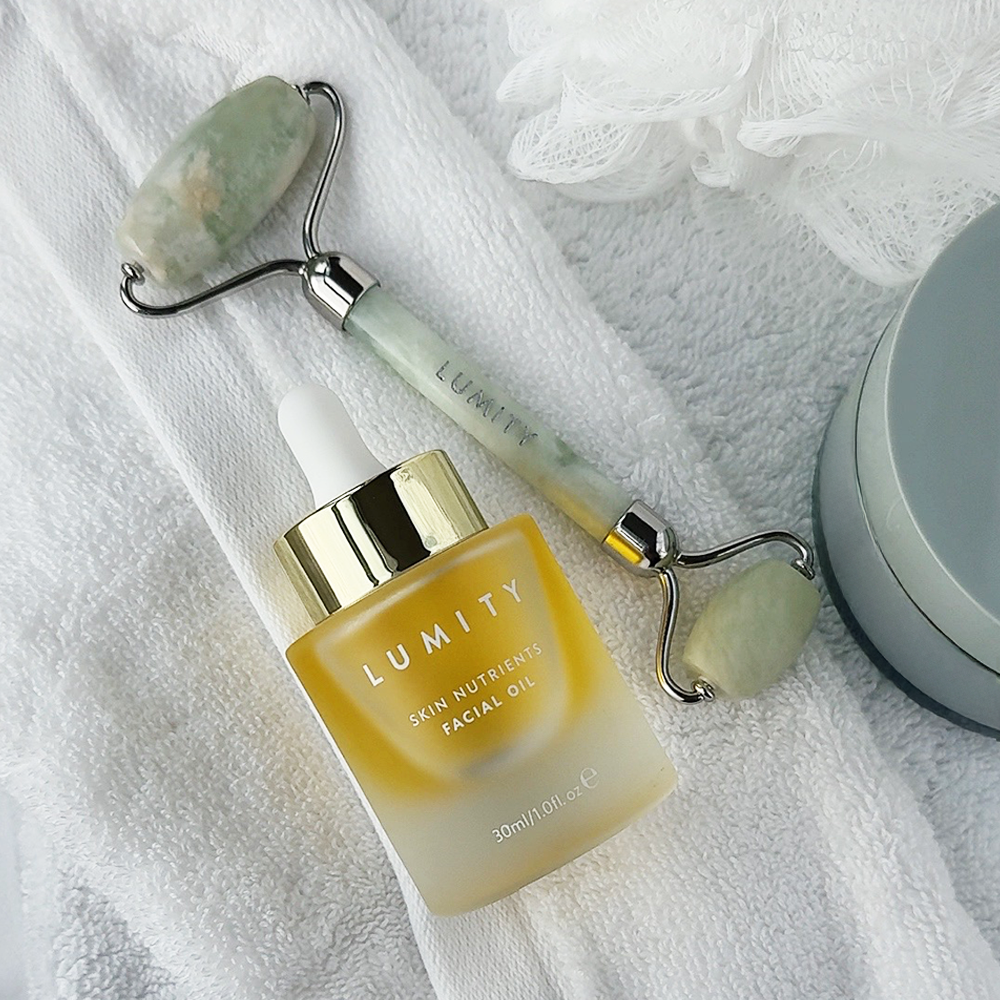 Lumity Facial Oil and Jade Roller on a white towel