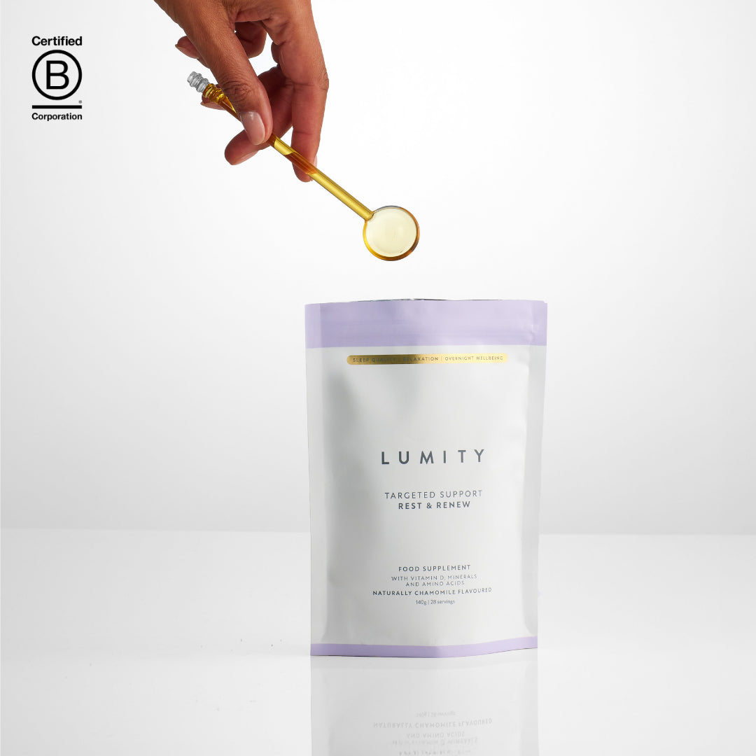 Hand holding a spoon with a scoop of supplement over a Lumity Targeted Support Rest & Renew Pouch