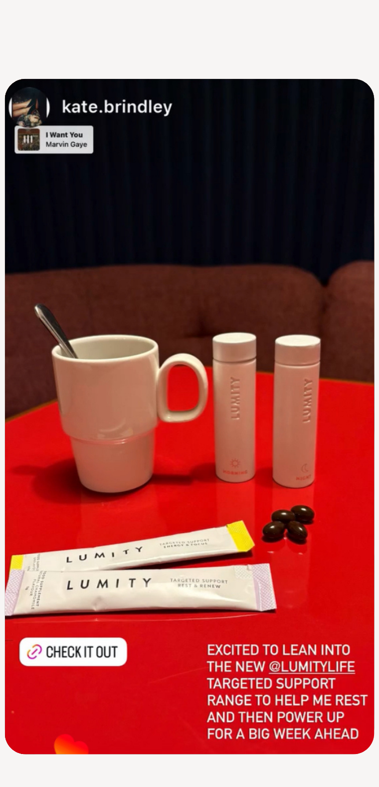 White ceramic mug with spoon beside Lumity Morning and Night supplement tubes, sachets, and softgel capsules on red table.