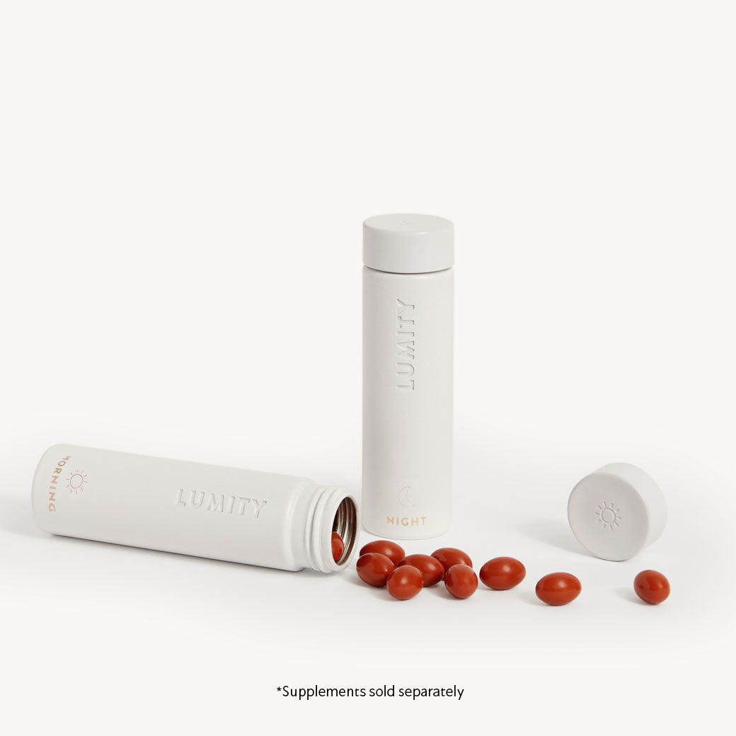 Minimalist white travel tubes labeled Morning and Night with red softgels spilling from the Morning container on white background