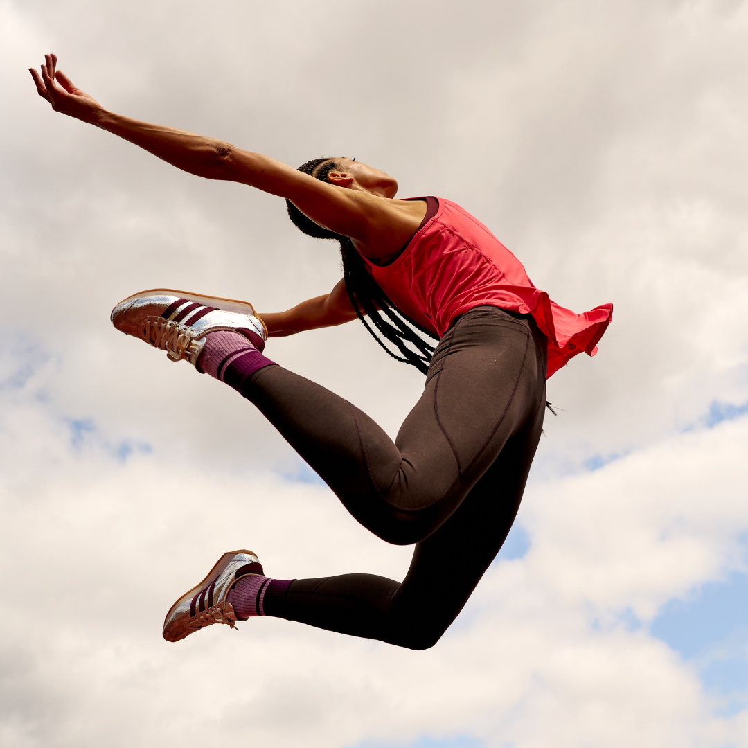 Image shows woman jumping in air in athleticwear