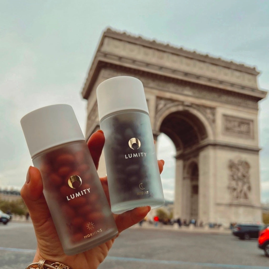 Lumity Morning & Night bottles held in front of the Arc de Triomphe in Paris