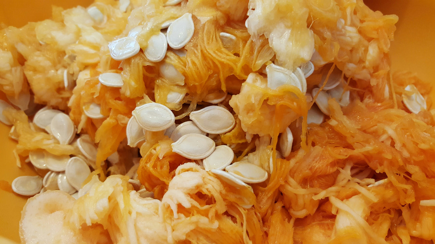 Close-up of a pumpkin's interior with seeds and fibrous strands.