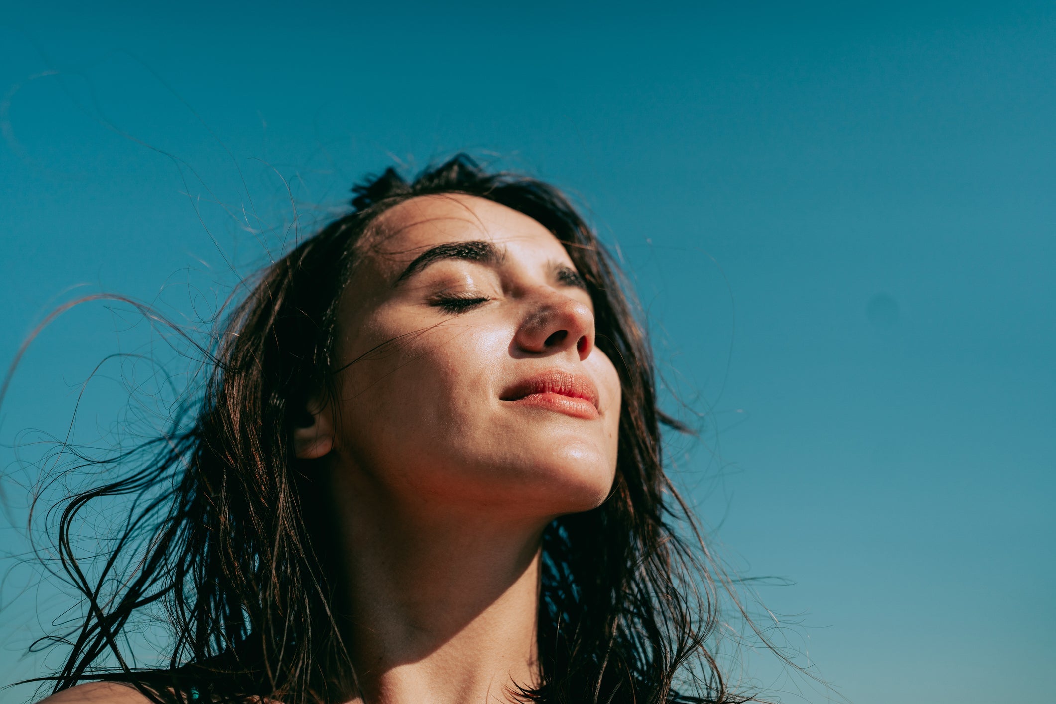 Image of women closing eyes in sunlight