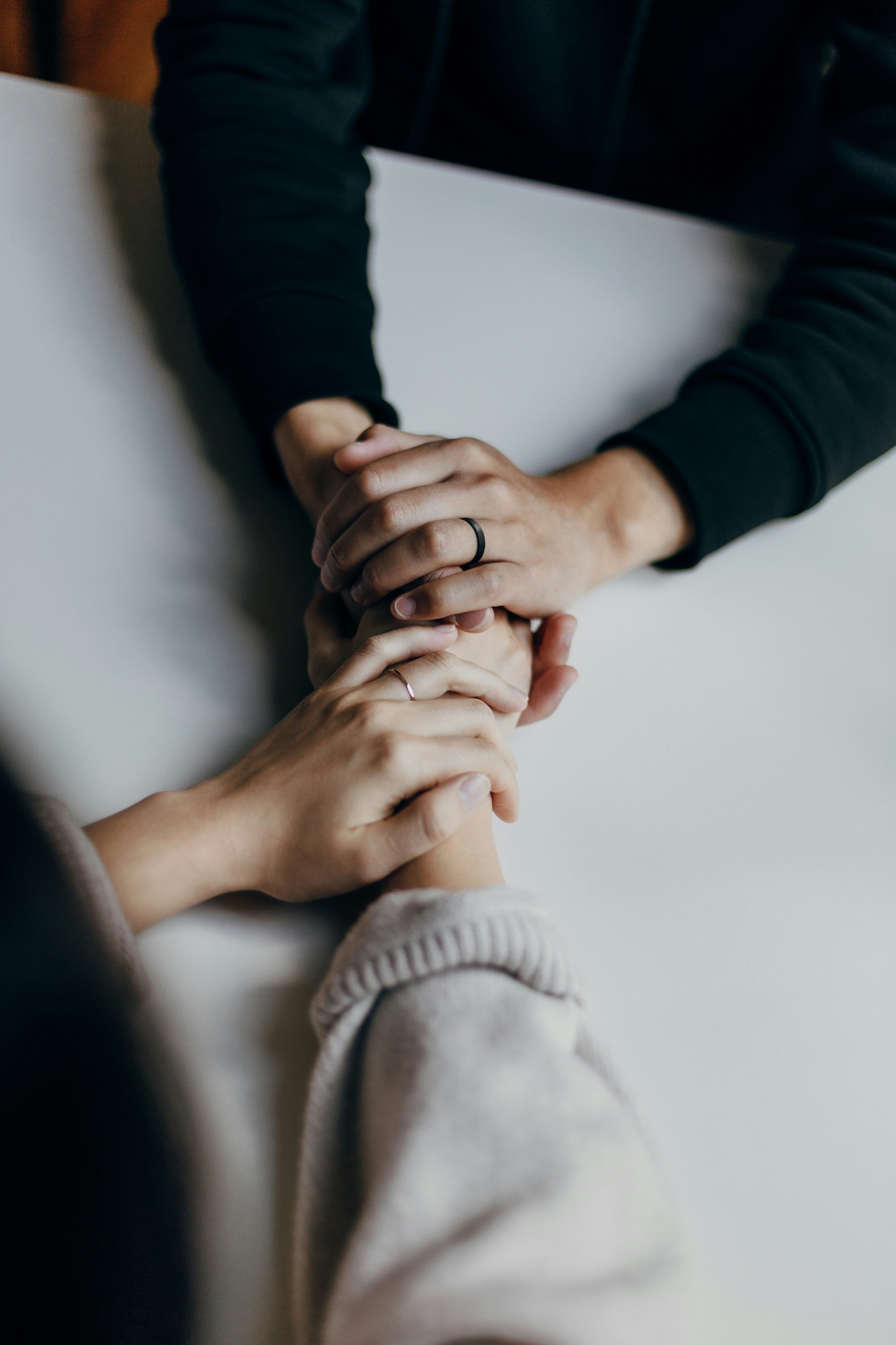 Two people holding hands, with their hands at the centre of a table