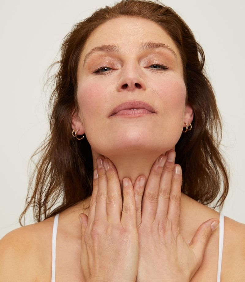 Woman using both hand to massage neck with Lumity life facial oil