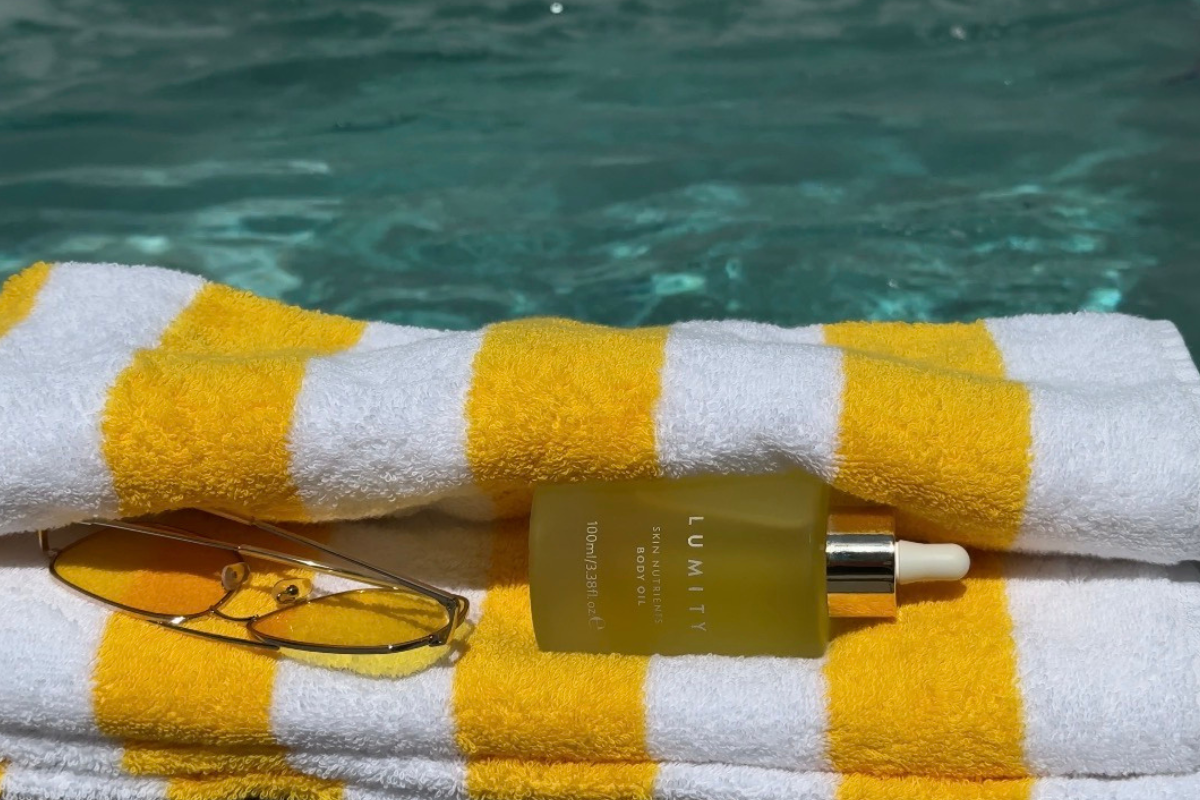 Lumity Body Oil on towel next to swimming pool