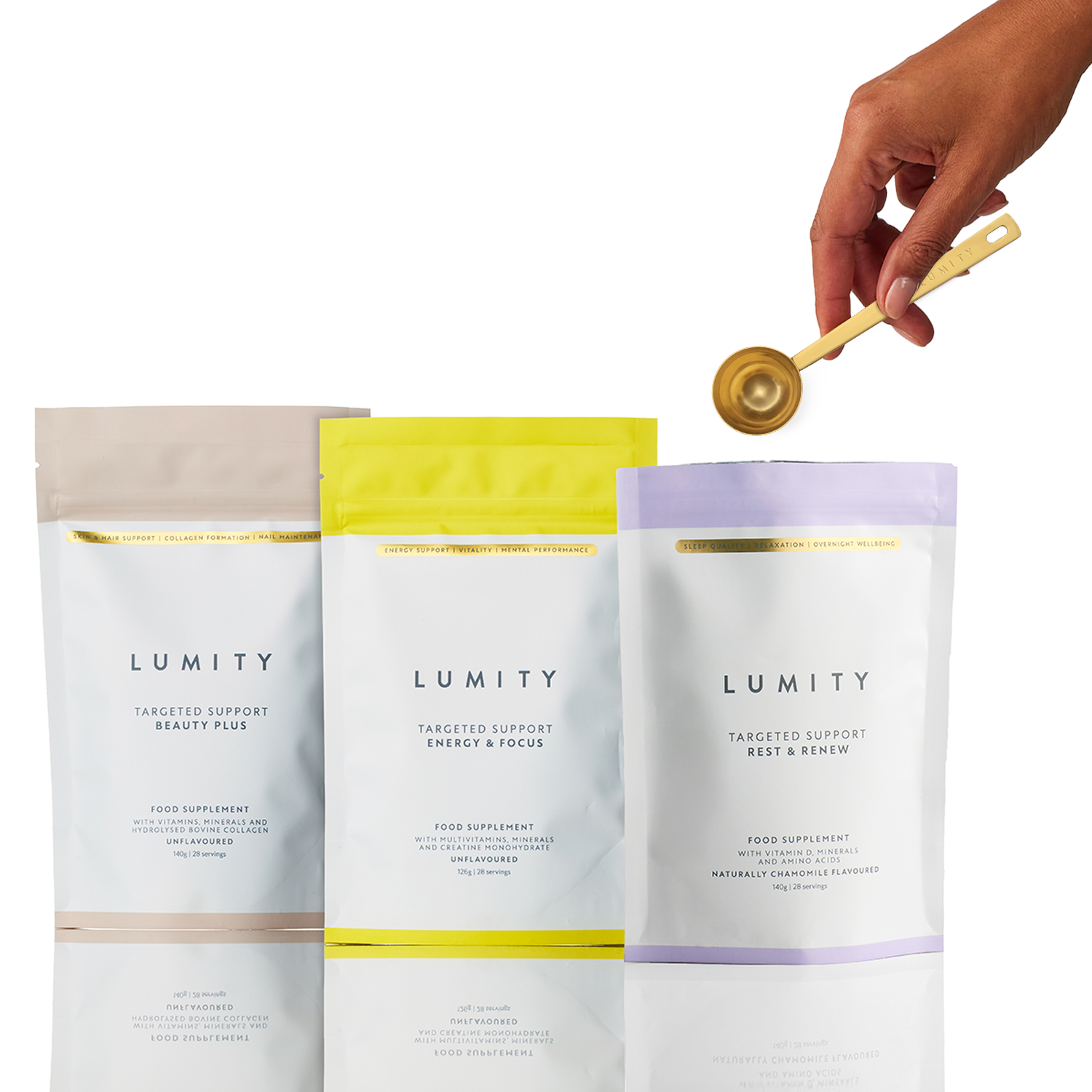 Hand holding gold metal Daily Ritual Scoop above three Lumity wellness supplement pouches in soft beige, yellow, and lavender colors