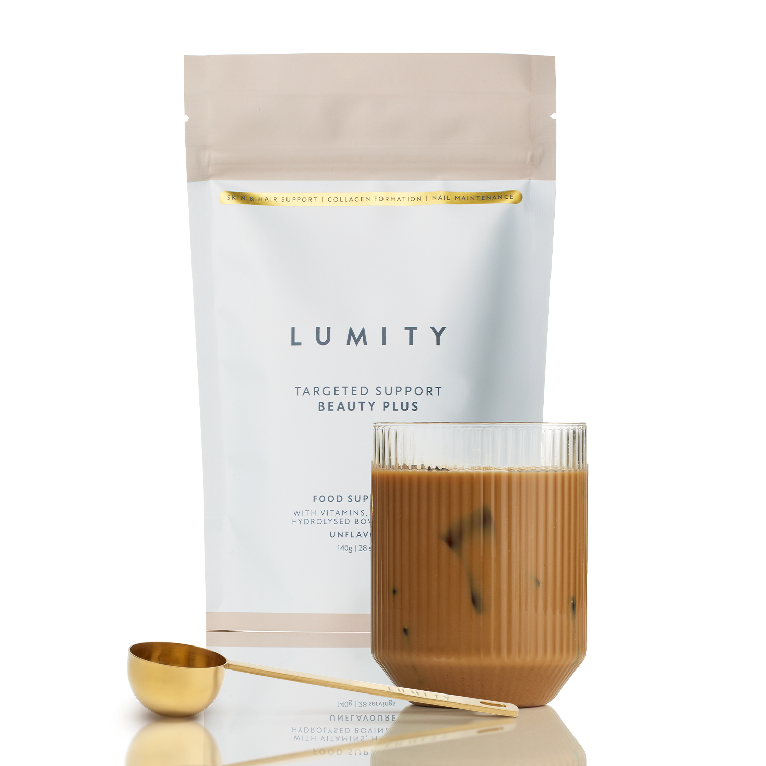 Glass of creamy beauty supplement drink beside a golden metal scoop and soft pastel resealable pouch for daily ritual use