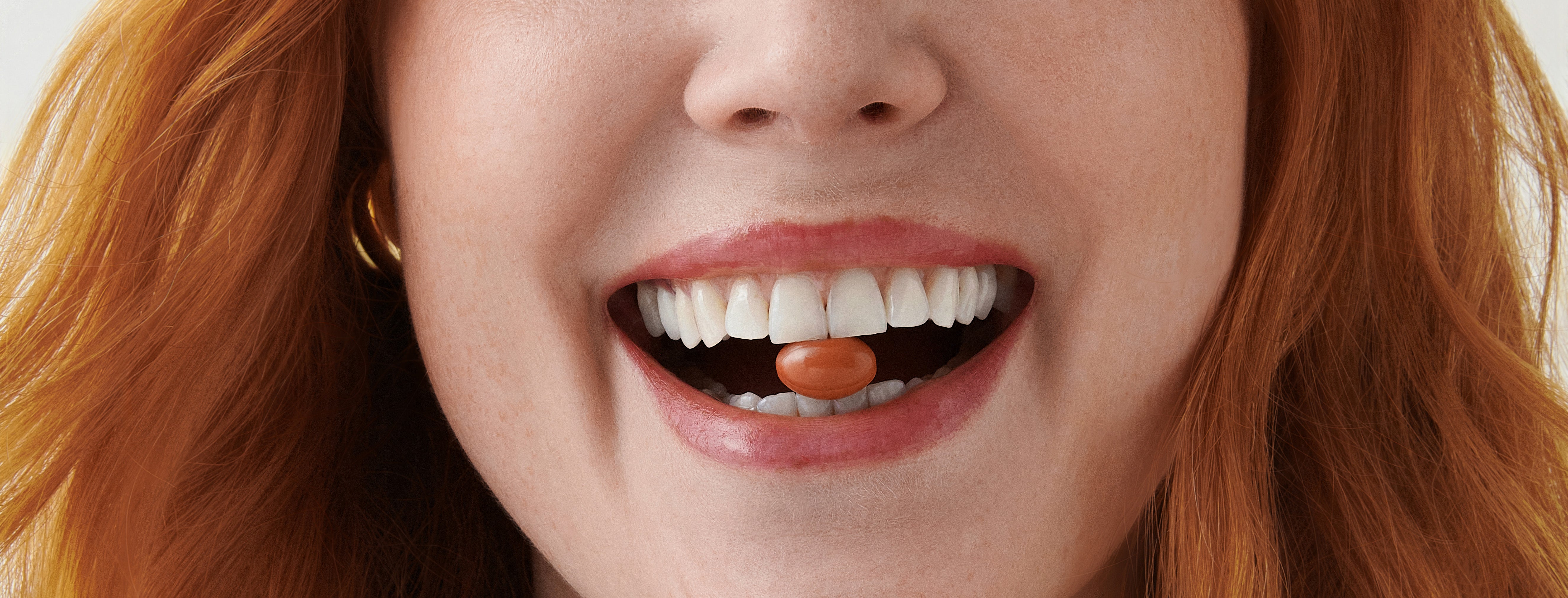 Woman smiling with supplement between her teeth