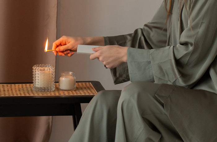 Person lighting a candle with a match in a cozy indoor setting